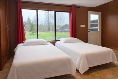 two beds in a room with a window at The Country Barn in Port Alberni