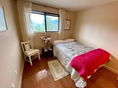 a bedroom with a bed and a window and a chair at The Country Barn in Port Alberni