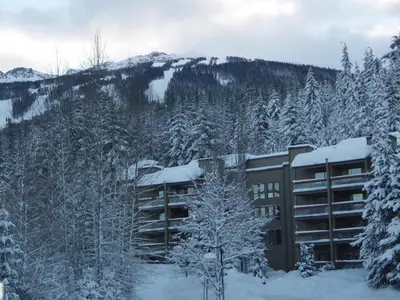 a building covered in snow in front of a mountain at Tantalus Resort Lodge in Whistler