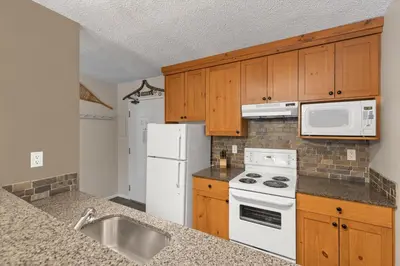 a kitchen with white appliances and wooden cabinets at Tantalus Resort Lodge in Whistler