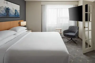 a bedroom with a large white bed and a chair at Delta Hotels Calgary Airport In-Terminal in Calgary