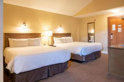 a hotel room with two beds and a desk at Irwin's Mountain Inn in Banff