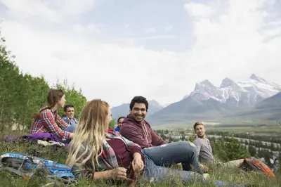 a group of people sitting on a hill with mountains in the background at Lodges at Canmore in Canmore