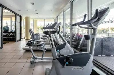 a gym with several cardio machines in a room at WaterFalls Hotel - Suite in Falls Downtown with pool in Victoria