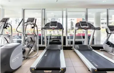 a gym with treadmills and elliptical machines at WaterFalls Hotel - Suite in Falls Downtown with pool in Victoria