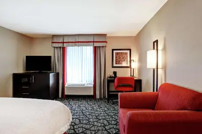 a hotel room with a bed and a red couch at Hampton Inn by Hilton Chilliwack in Chilliwack