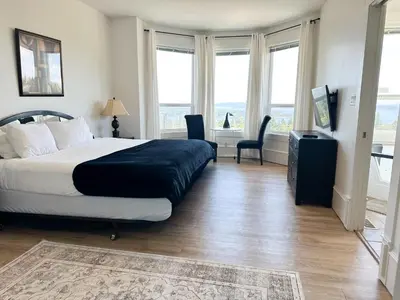 a bedroom with a bed and a desk and windows at Seaview Executive Home in Ladysmith