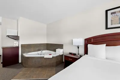 a hotel room with a bed and a bath tub at SureStay Plus Hotel by Best Western Hardisty in Hardisty