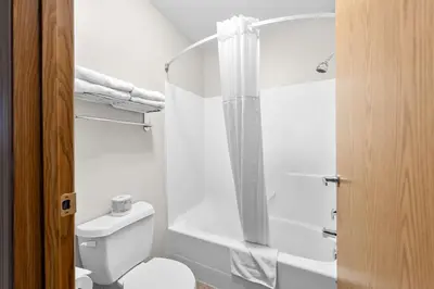 a white bathroom with a toilet and a shower at SureStay Plus Hotel by Best Western Hardisty in Hardisty