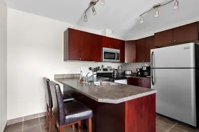 a kitchen with a white refrigerator and wooden cabinets at SureStay Plus Hotel by Best Western Hardisty in Hardisty