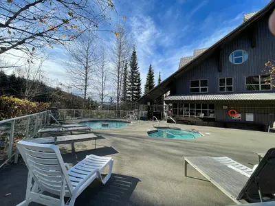 a patio with two chairs and a table and two pools at Best ski in ski out condo at Whistler in Whistler
