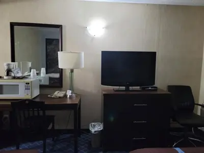 a hotel room with a television on a dresser with a desk at Super 8 North Red Deer in Red Deer