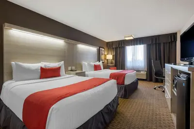 a hotel room with two beds and a television at Best Western Plus Village Park Inn in Calgary