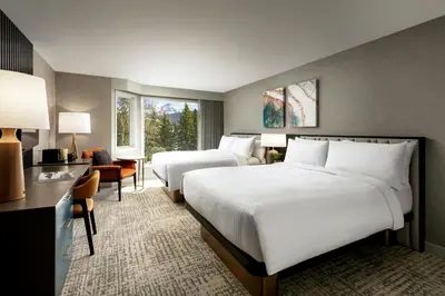a hotel room with two beds and a desk at Kananaskis Mountain Lodge, Autograph Collection in Kananaskis Village