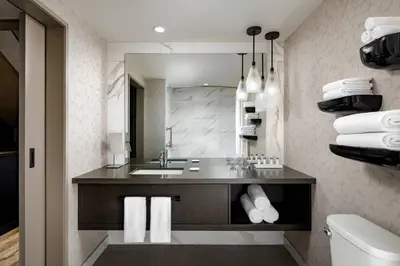 a bathroom with a sink and a mirror and towels at Kananaskis Mountain Lodge, Autograph Collection in Kananaskis Village