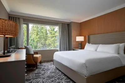 a hotel room with a bed and a desk and a window at Kananaskis Mountain Lodge, Autograph Collection in Kananaskis Village