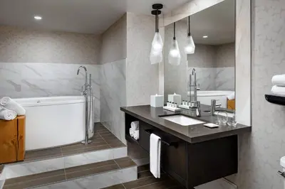 a bathroom with a tub and a sink and a mirror at Kananaskis Mountain Lodge, Autograph Collection in Kananaskis Village