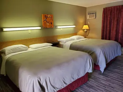a hotel room with two beds and a clock on the wall at Stars Inn - Motel in Fort Saskatchewan