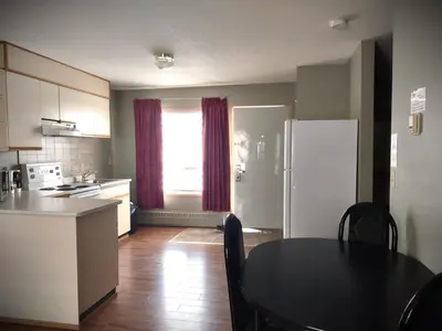 a kitchen with a black table and a refrigerator at Stars Inn - Motel in Fort Saskatchewan