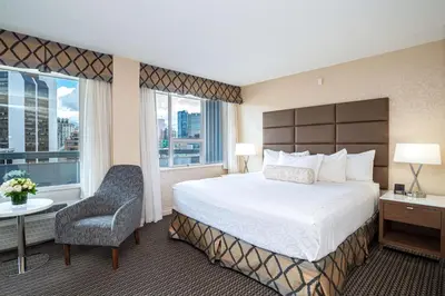 a hotel room with a bed and a chair and a window at Best Western Premier Chateau Granville Hotel & Suites & Conference Centre in Vancouver