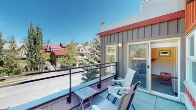 a balcony with two chairs and a table at 1BR in Lake Placid Lodge, Steps to Creekside Gondola, Shared Pool and Hot Tub, Lounge Access in Whistler