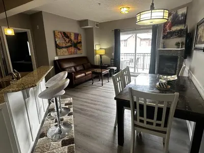 a living room with a table and chairs and a couch at Luxury Two Queen Beds Condo - Grande Rockies Resort Indoor Parking Pool Hot tub GYM in Canmore