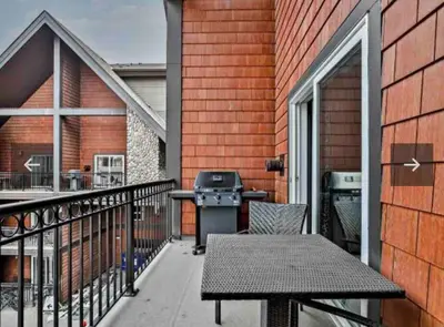a patio with a grill and a table on a balcony at Luxury Two Queen Beds Condo - Grande Rockies Resort Indoor Parking Pool Hot tub GYM in Canmore