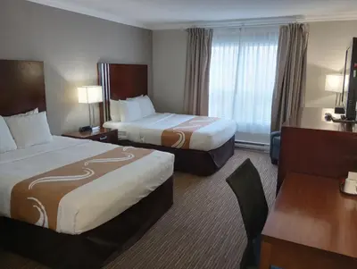 a hotel room with two beds and a desk at Quality Inn Downtown Inner Harbour in Victoria