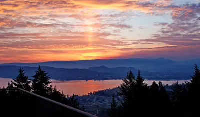 a sunset with a view of a city and a lake at Honeymoon Suite in West Kelowna