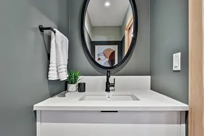 a bathroom with a white sink and a mirror at Ravens Crest Lodge - Stunning Views Perfectly Located on Main Street in Canmore