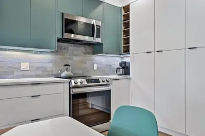 a kitchen with white cabinets and a blue chair at Ravens Crest Lodge - Stunning Views Perfectly Located on Main Street in Canmore