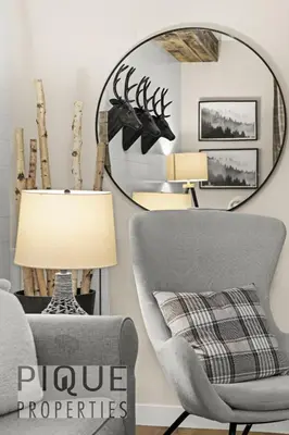 a living room with a chair and a mirror at Mystic Mountain Chalet, Heated Outdoor Pool & Hot Tub, Free Parking, Fast Wifi! in Canmore