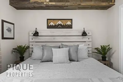 a bedroom with a white bed with a wooden headboard at Mystic Mountain Chalet, Heated Outdoor Pool & Hot Tub, Free Parking, Fast Wifi! in Canmore