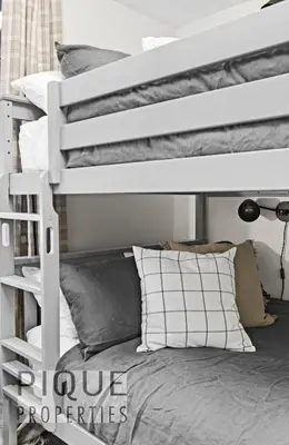 a white bunk bed in a room with pillows at Mystic Mountain Chalet, Heated Outdoor Pool & Hot Tub, Free Parking, Fast Wifi! in Canmore