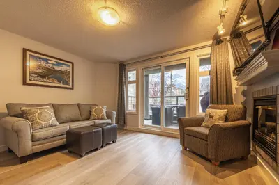 a living room with a couch and a fireplace at Mountain View One Bedroom Vacation Suite - WindTower 119 in Canmore