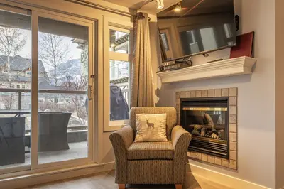 a living room with a chair and a fireplace at Mountain View One Bedroom Vacation Suite - WindTower 119 in Canmore