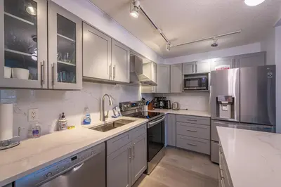 a kitchen with white cabinets and stainless steel appliances at Mountain View One Bedroom Vacation Suite - WindTower 119 in Canmore