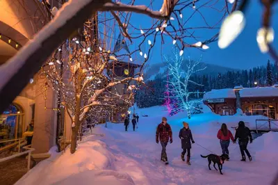 a group of people walking a dog in the snow at 2BR in Crystal Forest, Ski In, Ski Out, Fireplace, Private Hot Tub, Steps to the Village in Sun Peaks