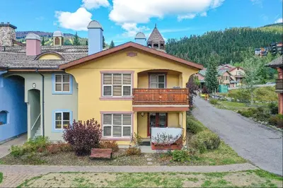 a yellow house with a balcony on top of it at 2BR in Crystal Forest, Ski In, Ski Out, Fireplace, Private Hot Tub, Steps to the Village in Sun Peaks