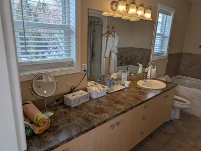 a bathroom with two sinks and a toilet and a mirror at Salish B&B and Spa in West Kelowna
