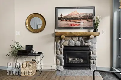 a living room with a fireplace with a picture on the wall at Alpine Loft with Pool, Hot Tub & Mountain Views in Canmore