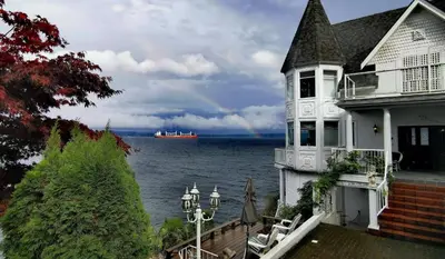 a house with a view of the water and a ship at Walkon Waterfront Castle Cove Inn in Chemainus