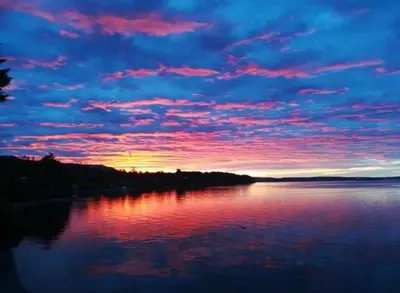 a sunset over a lake with a pink at Walkon Waterfront Castle Cove Inn in Chemainus