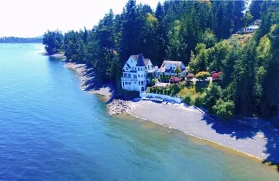 an aerial view of a house on an island in the water at Walkon Waterfront Castle Cove Inn in Chemainus