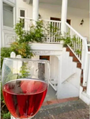 a glass of red wine in front of a house at Walkon Waterfront Castle Cove Inn in Chemainus