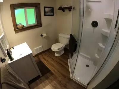 a bathroom with a toilet and a glass shower at 4 Mile Creek Cabin (Creekside) in Nelson