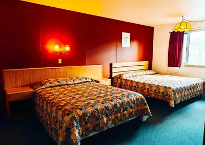 a hotel room with two beds and red walls at Cozy Corner Motel & Restaurant in Haines Junction