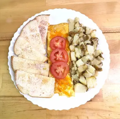 a plate of pizza with tomatoes and mushrooms on a table at Cozy Corner Motel & Restaurant in Haines Junction