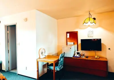a room with a desk with a computer and a television at Cozy Corner Motel & Restaurant in Haines Junction