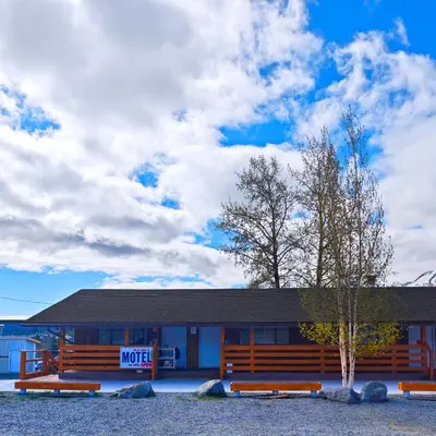 a motel with benches in front of a building at Cozy Corner Motel & Restaurant in Haines Junction